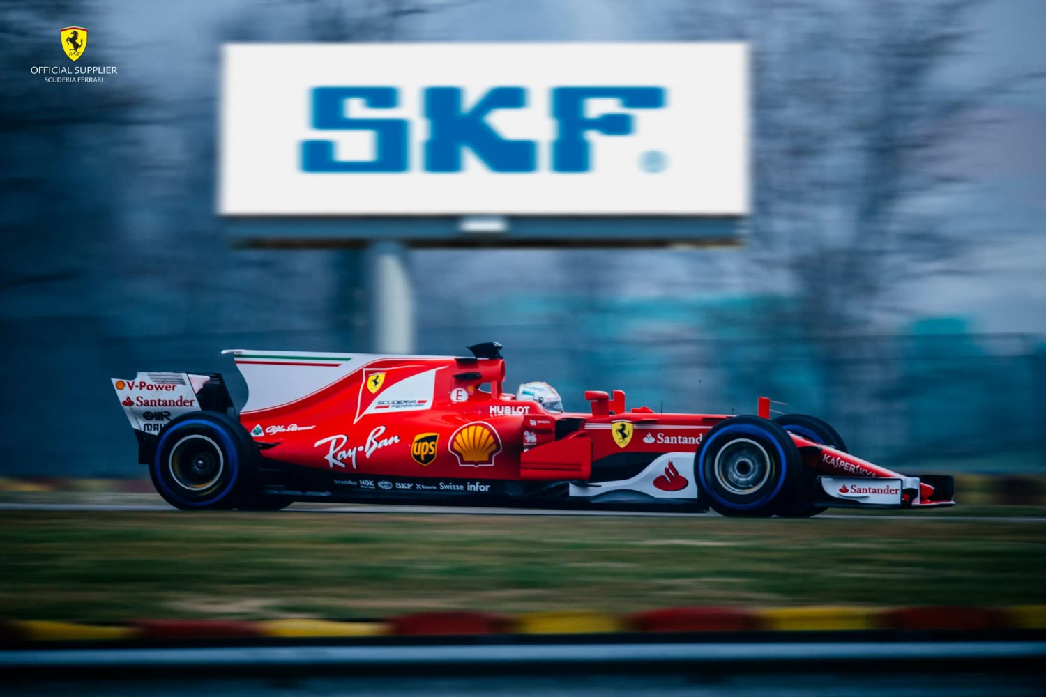 A Scuderia Ferrari Formula 1 car passing an SKF billboard